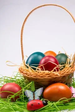 Easter eggs in wicker basket on white Stock Photos