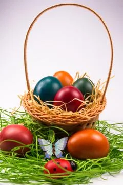 Easter eggs in wicker basket on white Stock Photos