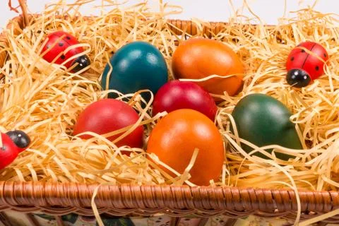 Easter eggs in wicker basket on white Stock Photos