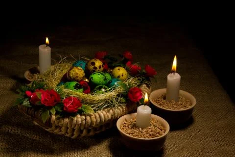 Easter eggs in wooden basket with Easter candles Stock Photos