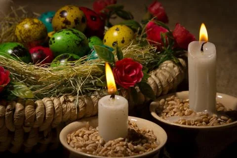 Easter eggs in wooden basket with Easter candles Stock Photos