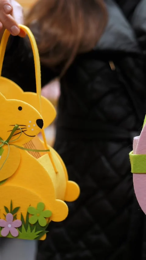 Easter fair. close-up. decorative Easter gifts, felt bunny bags in female hands. Video stock 313799663