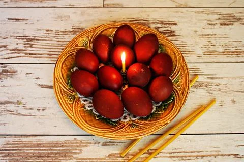 Easter festive composition of candle and painted chicken eggs in ceramic plat Stock Photos