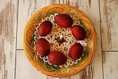 Easter festive composition of candle and painted chicken eggs in ceramic plat Stock Photos