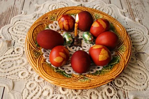 Easter festive composition of candle and painted chicken eggs in ceramic plat Stock Photos