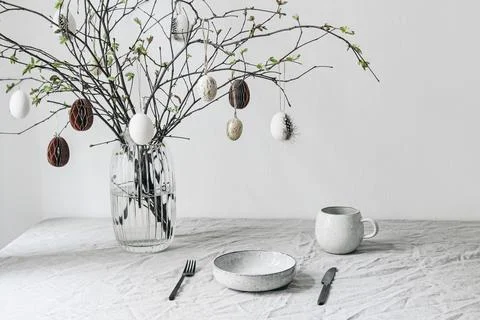 Easter festive table setting. Fresh branches in vase decorated by paper Fotos Stock