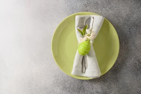 Easter festive table setting green yellow plate, spring flowers and green egg Stock Photos
