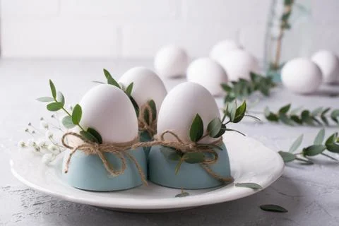Easter  festive table setting with white chicken  eggs in eggs cups, leaf Foto stock