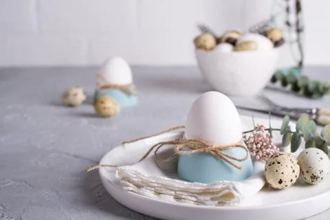 Easter  festive table setting with white chicken  eggs in eggs cups, leaf Stock Photos