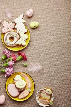 Easter flat lay with copy space. Decorated Easter cookies, pink flowers with Stock Photos
