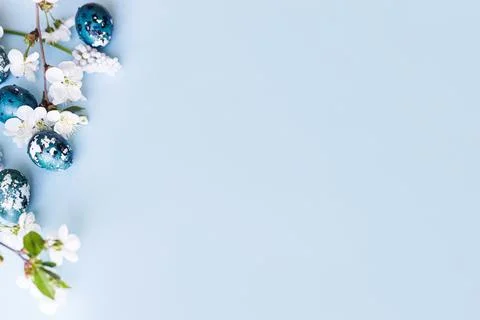 Easter flat lay. Stylish easter eggs and cherry flowers on blue background... Stock Photos