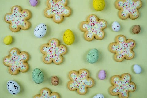 Easter flower biscuits and candy eggs on flat colored background .Easter holi Stock Photos