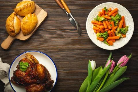 Easter food on dark rustic table pastel colored eggs roasted chicken and Foto stock