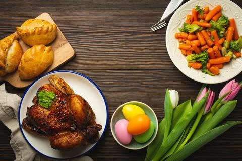 Easter food on dark rustic table pastel colored eggs roasted chicken and Foto stock