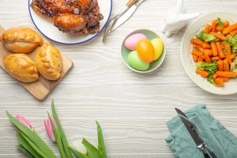 Easter food on white rustic table: pastel colored eggs, roasted chicken Stock Photos