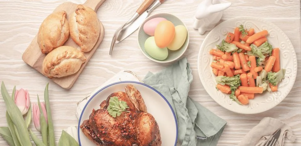Easter food on white rustic table pastel colored eggs roasted chicken and Foto stock