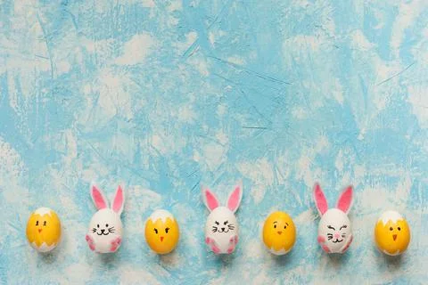 Easter frame, easter eggs decorated as bunnies and chicks on sky blue background Stock Photos