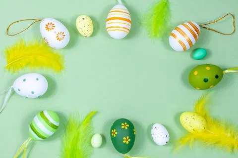 Easter frame with eggs and feathers on a green background. Minimal concept. View Stock Photos