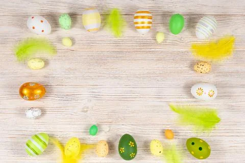 Easter frame with eggs and feathers on a light wooden background. Minimal Stock Photos