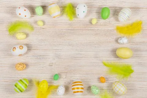 Easter frame with eggs and feathers on a light wooden background. Minimal Stock Photos