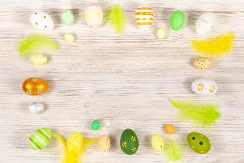 Easter frame with eggs and feathers on a light wooden background. Minimal Foto stock