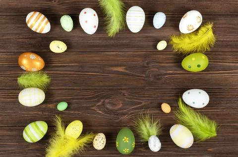 Easter frame with eggs and feathers on a dark wooden background. Minimal concept Stock Photos