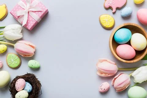 Easter frame with eggs, gift box and tulip on a colored background. The minim Foto stock