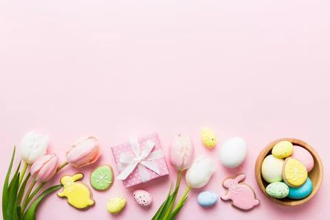 Easter frame with eggs, gift box and tulip on a colored background. The minim Stock Photos