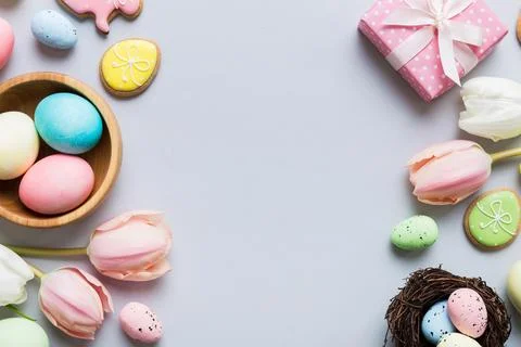 Easter frame with eggs, gift box and tulip on a colored background. The minim Stock Photos