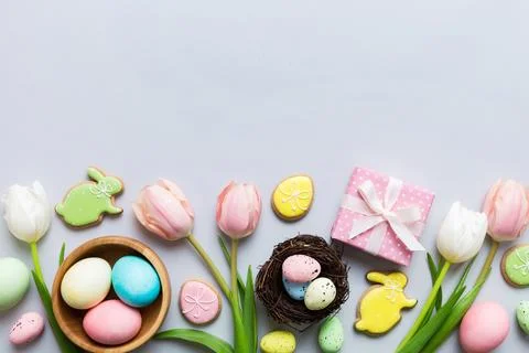 Easter frame with eggs, gift box and tulip on a colored background. The min.. Stock Photos