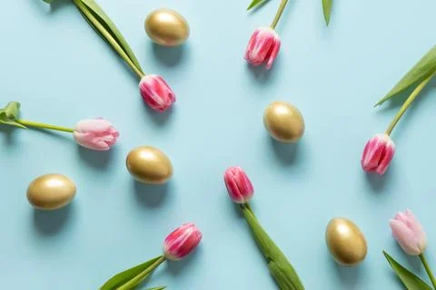 Easter frame with eggs, tulips on blue. Space for text. Stock Photos