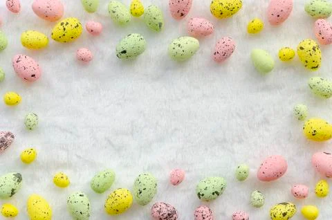 Easter frame pink, green and yellow colors eggs fluffy white wool background Stock Photos
