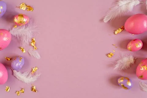 Easter frame, violet and pink easter eggs with golden foil and white feathers on Stock Photos