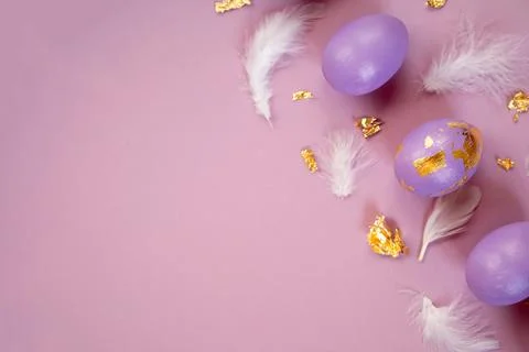 Easter frame with violet, very peri Easter eggs, feathers and golden foil on the Stock Photos