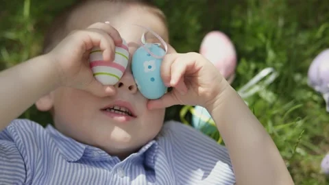Easter funny boy face covered eyes with colorful easter eggs. little kid lying Video stock 232541203