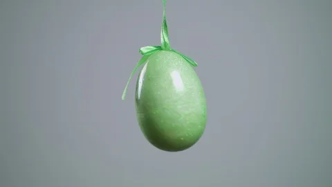 Easter green eggs with white folk pattern, hang on red ribbons with bow on white Stock Footage 106635159