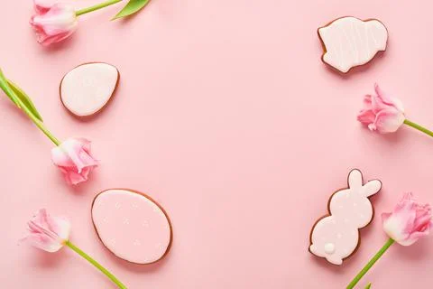 Easter greeting card with easter gingerbread eggs and tulip flowers over pink Stock Photos