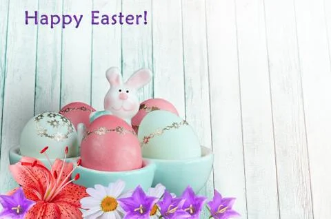 Easter greeting. Eggs in a stand with a rabbit and flowers 写真素材