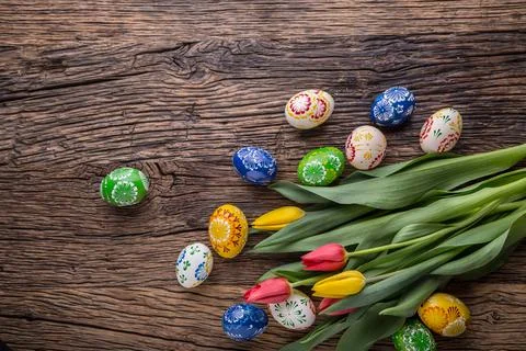 Easter. Hand made easter eggs and spring tulips on old wooden table Stock Photos