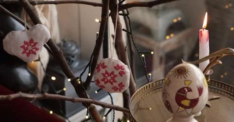 Easter handcrafted decorations displayed on a branch with warm candlelight .. Foto stock