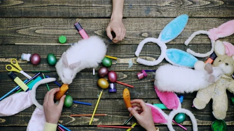 Easter. Hands play with whote rabbit, painting Easter eggs. Top view. Stock Footage 143369145