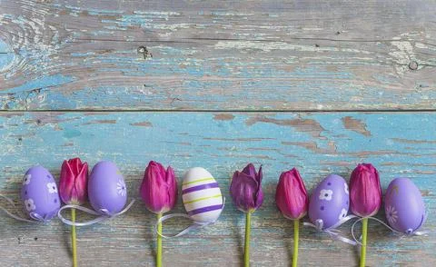 Easter holiday background; Frame of easter eggs and purple tulips on old bl.. Stock Photos