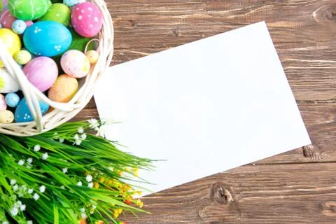 Easter holiday background with paper note, easter eggs in basket and flowers  Stock-Fotos