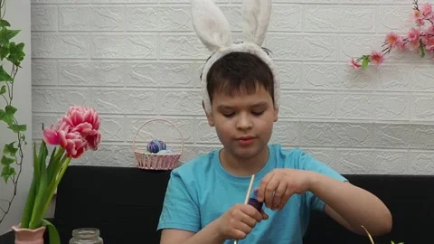Easter holiday.  bunny ears. A boy  paints an Easter egg. Preparing for Easter 스톡 동영상 173751045