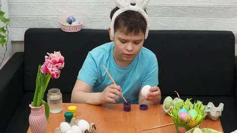 Easter holiday.  bunny ears. A boy  paints an Easter egg. Preparing for Easter 스톡 동영상 173751398