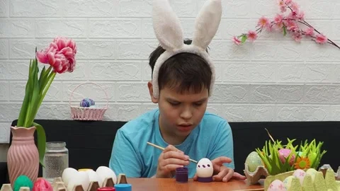 Easter holiday.  bunny ears. A boy  paints an Easter egg. Preparing for Easter 스톡 동영상 173753975
