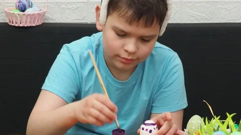 Easter holiday.  bunny ears. A boy  paints an Easter egg. Preparing for Easter 스톡 동영상 173754582