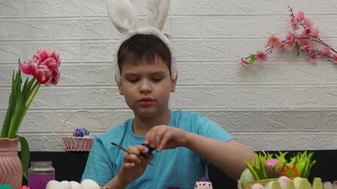 Easter holiday.  bunny ears. A boy  paints an Easter egg. Preparing for Easter 스톡 동영상 173755169