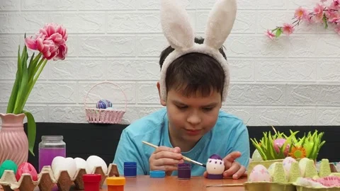 Easter holiday.  bunny ears. A boy  paints an Easter egg. Preparing for Easter Stock Footage 173755583