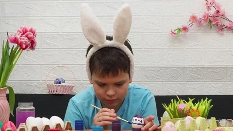 Easter holiday.  bunny ears. A boy  paints an Easter egg. Preparing for Easter 스톡 동영상 173755597